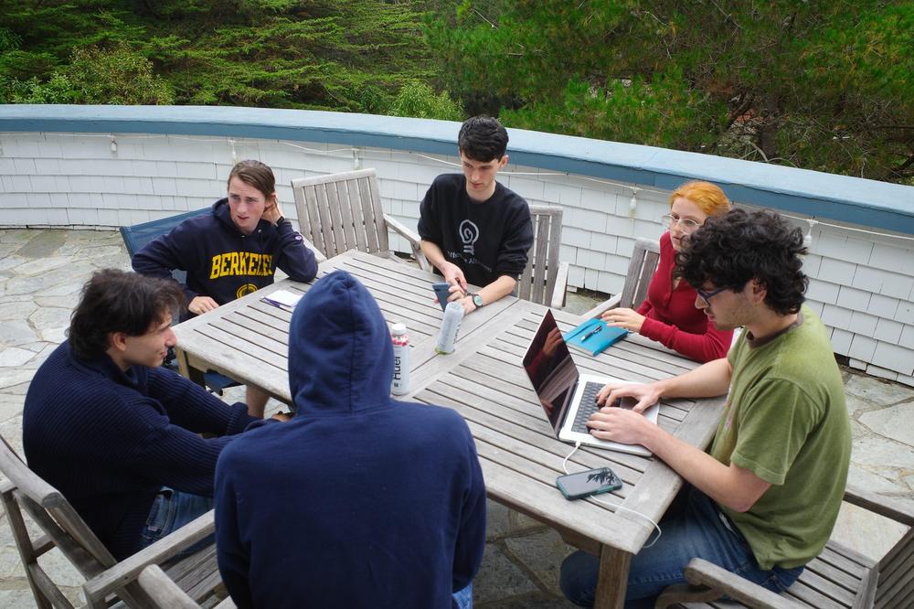 Members gathered around an outdoor table during a discussion workshop.